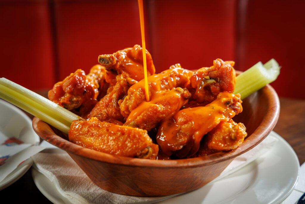 Hot sauce drizzled on a bowl of chicken wings.