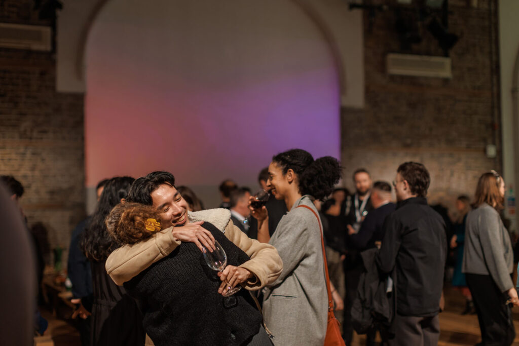 Joyful embrace at a lively social gathering with drinks.