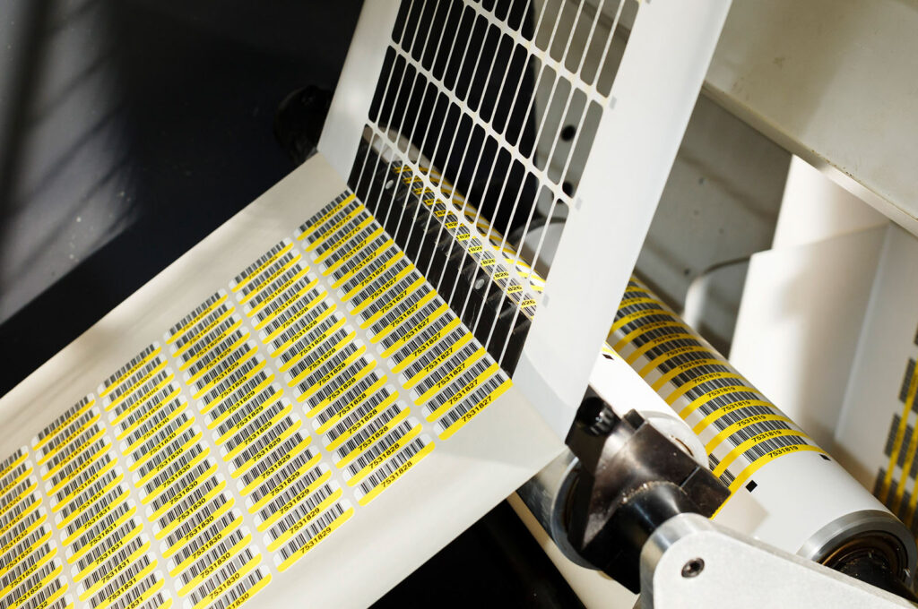 Machine printing rolls of yellow barcode labels.