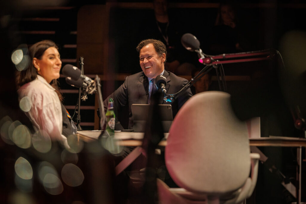 Man and woman laughing during a podcast recording.