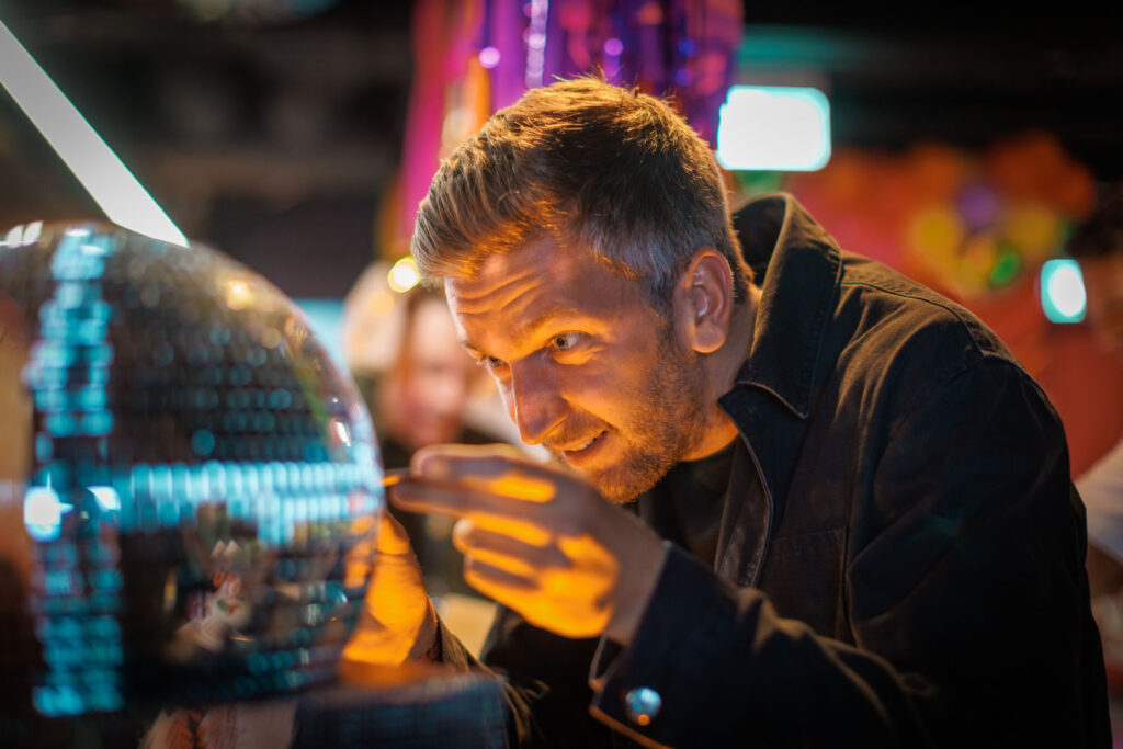 Man captivated by a glowing, reflective sphere.
