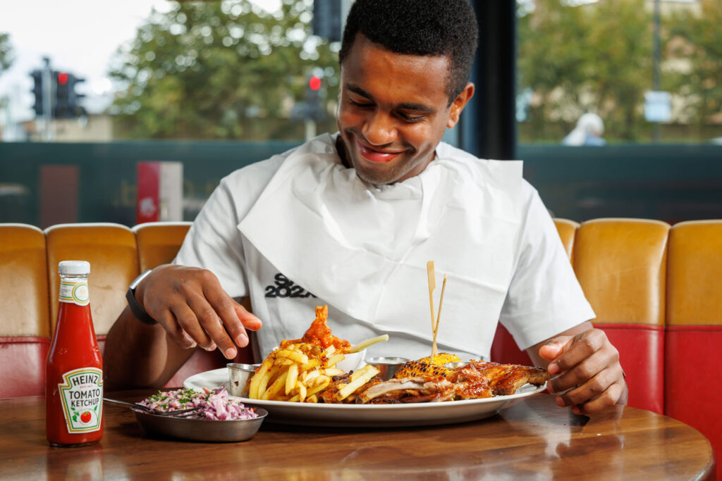 Man in bib happily eating chicken and fries.