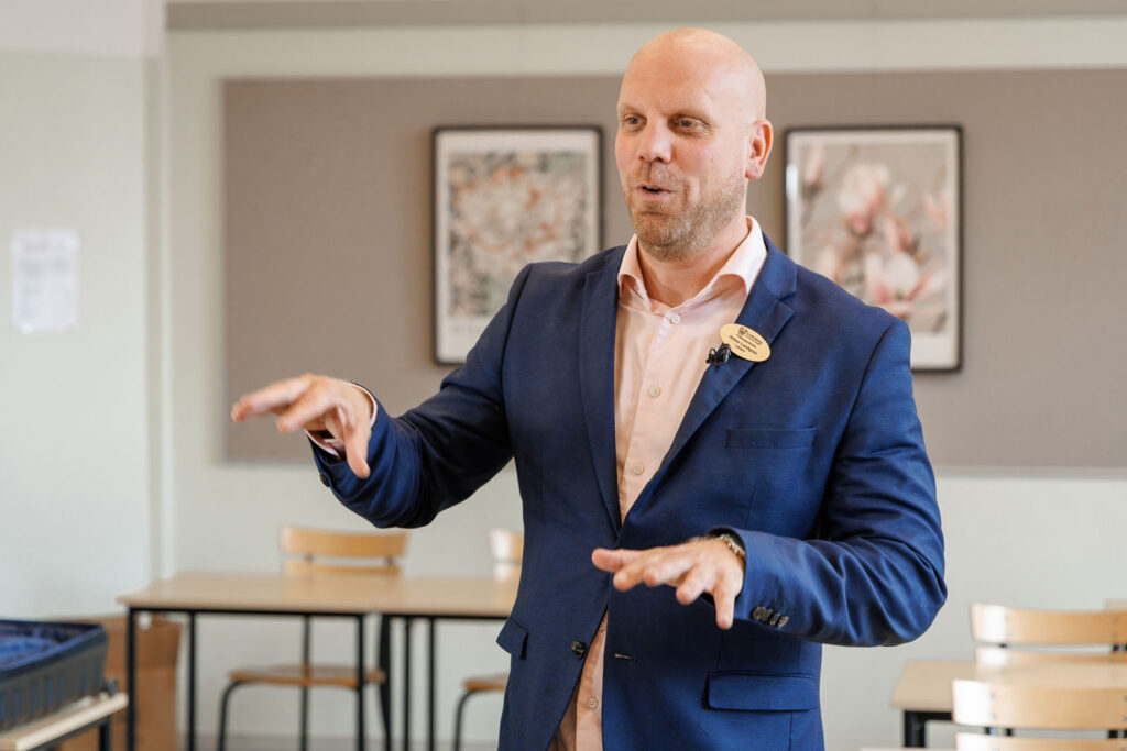 Man in suit giving a presentation, gesturing.