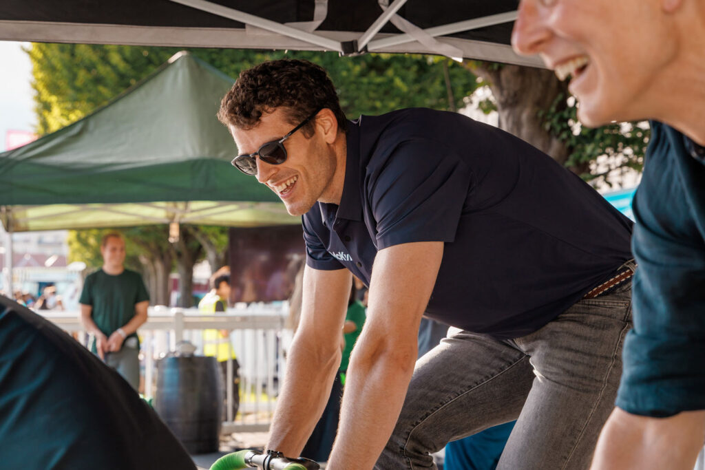 Man in sunglasses smiles while leaning on a bicycle outdoors.