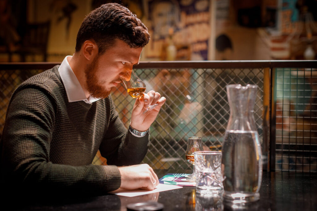 Man intently smells whiskey during a tasting session.