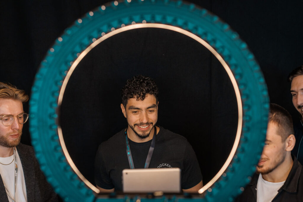 Man smiling at tablet, framed by ring light.