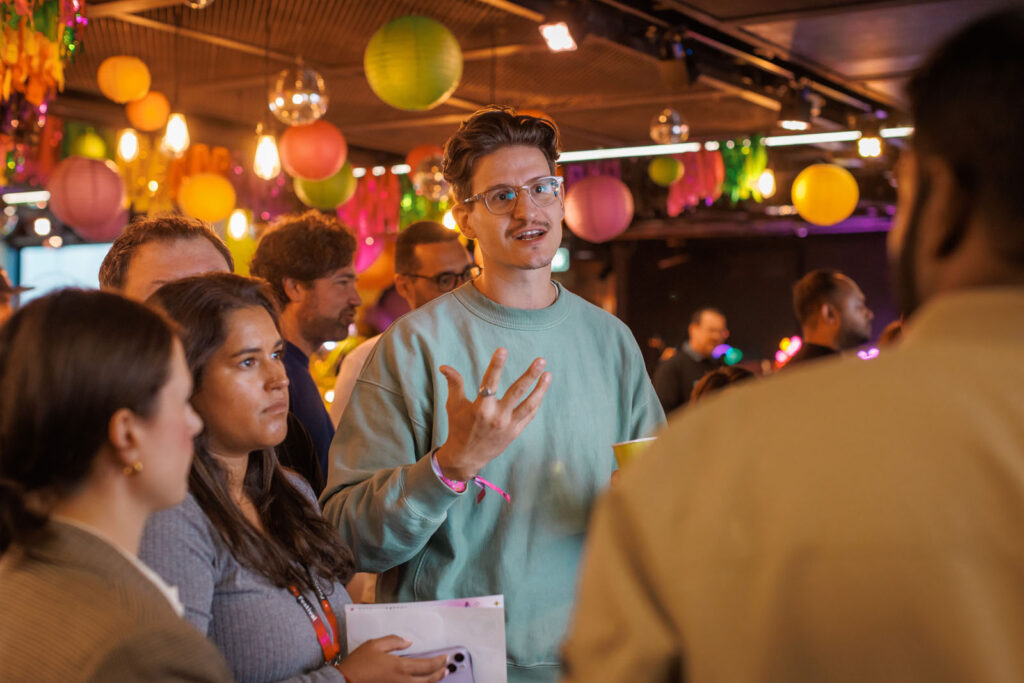 Man speaking to a group in a vibrant, decorated room.