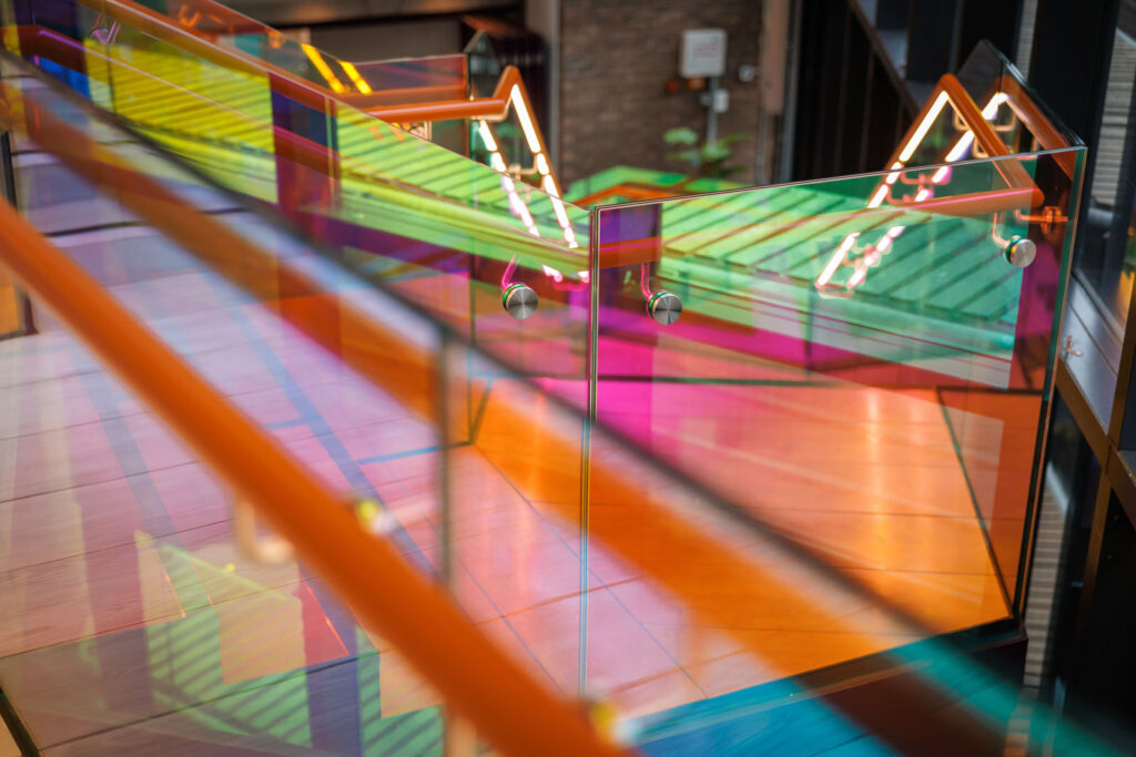 Modern colorful glass staircase with vibrant reflections.