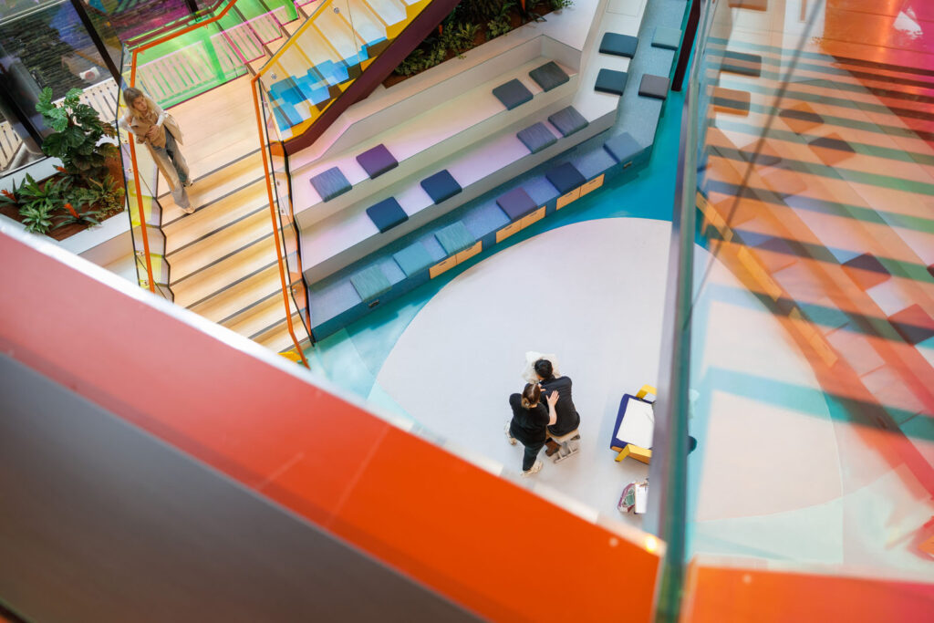 Modern, colorful interior with people on stairs and floor.