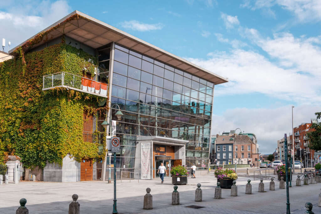 Modern glass and ivy building in a bustling city street.