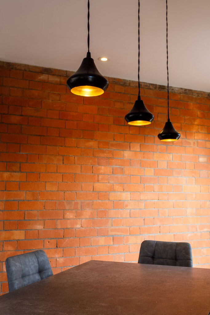 Modern interior with brick wall, table, and pendant lights.