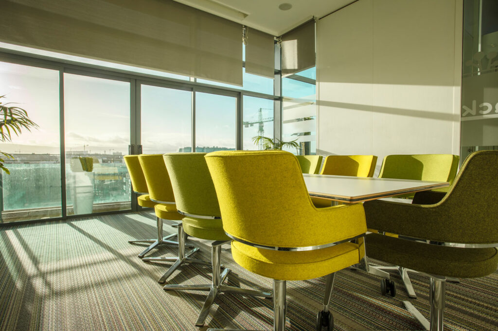 Modern meeting room with green chairs and city view.