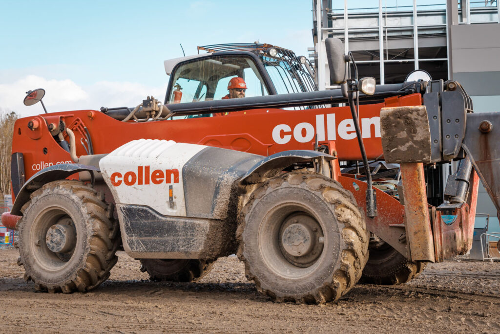 Orange Collen telehandler on a muddy construction site.