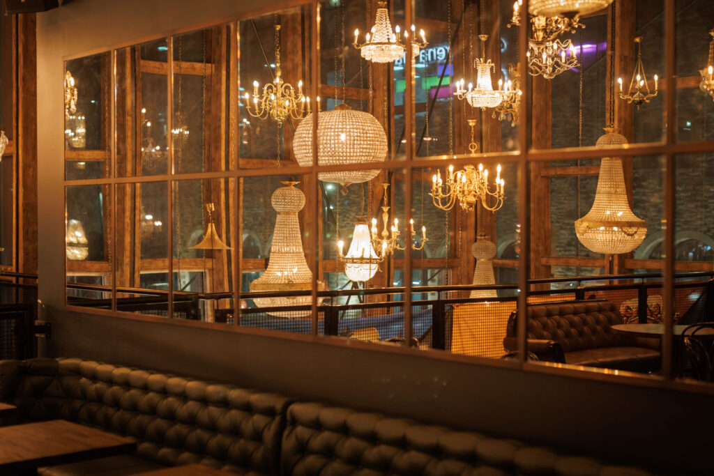 Ornate chandeliers illuminate a stylish interior with plush seating.