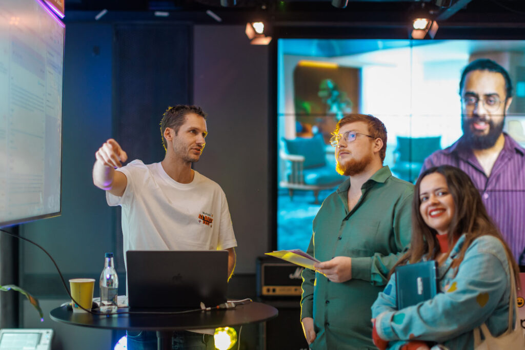 People at a tech event, one pointing at screen.