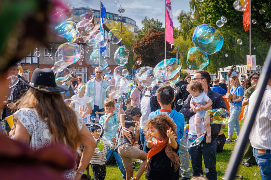 People enjoying a sunny outdoor event with many bubbles.