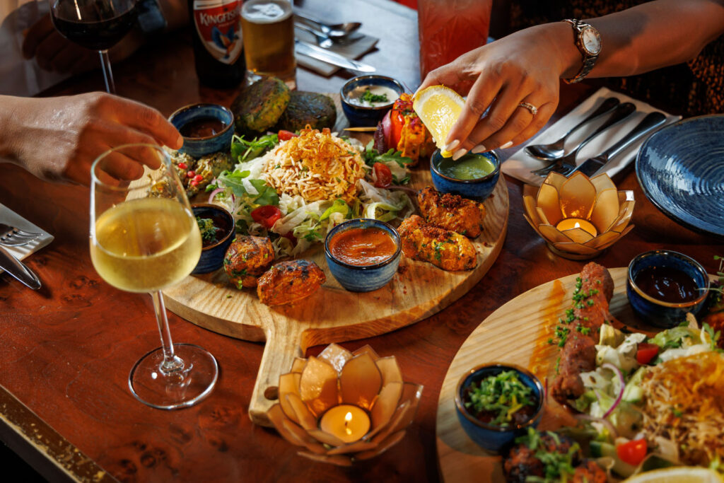 People enjoying a vibrant Indian feast with drinks.