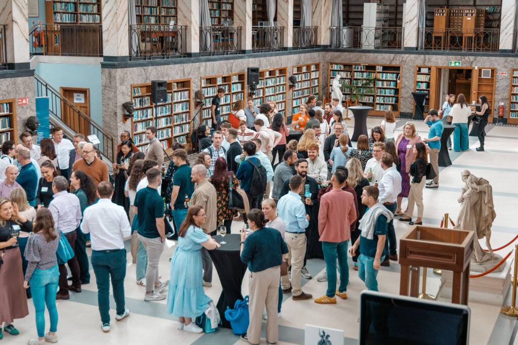 People gather and socialize in a large, ornate library.