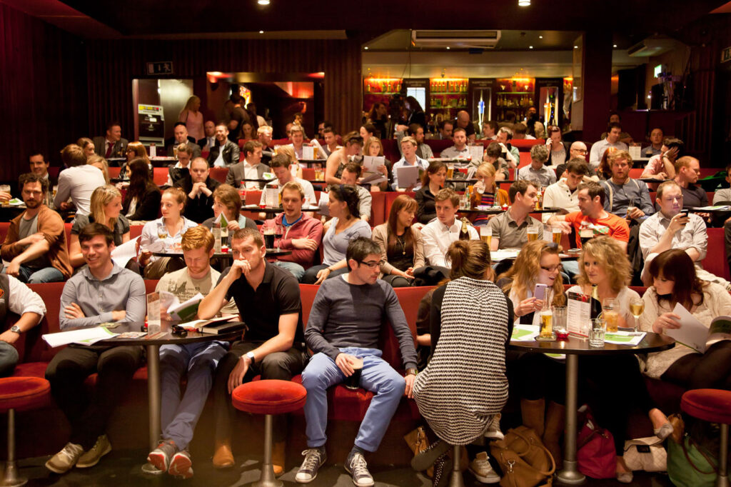 People gathered, drinking and socializing in a dimly lit venue.