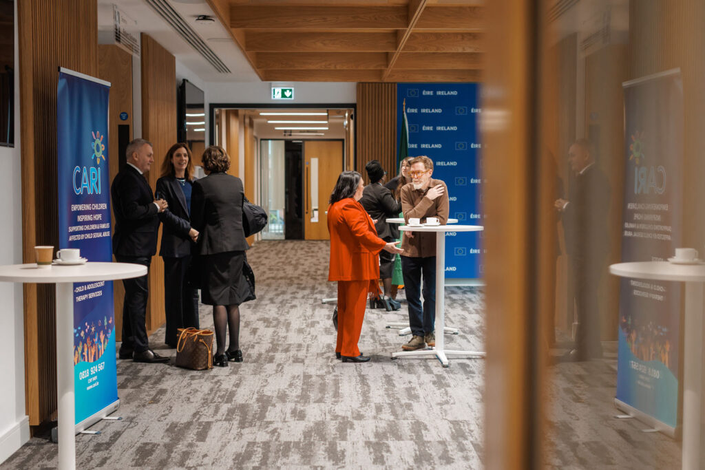People networking at an event with CARI and Ireland banners.