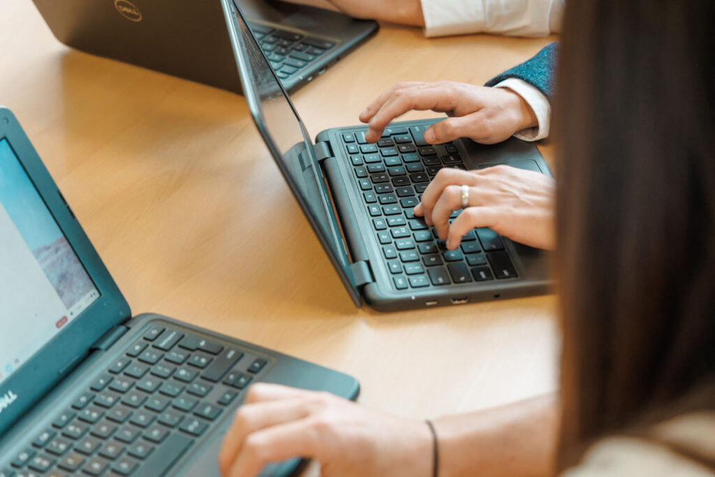 People typing on laptops at a table.