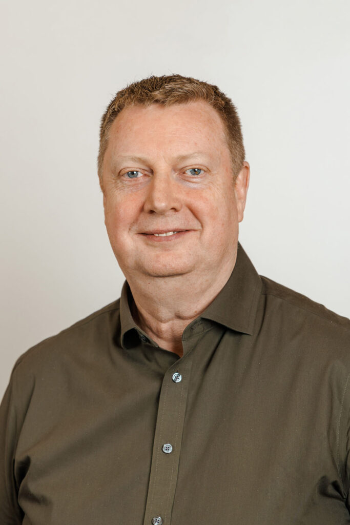 Portrait of a smiling man in a green shirt.