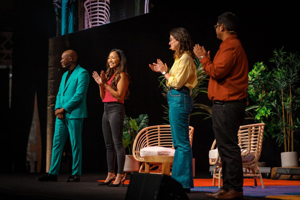 Presenters clapping on stage at a professional event.