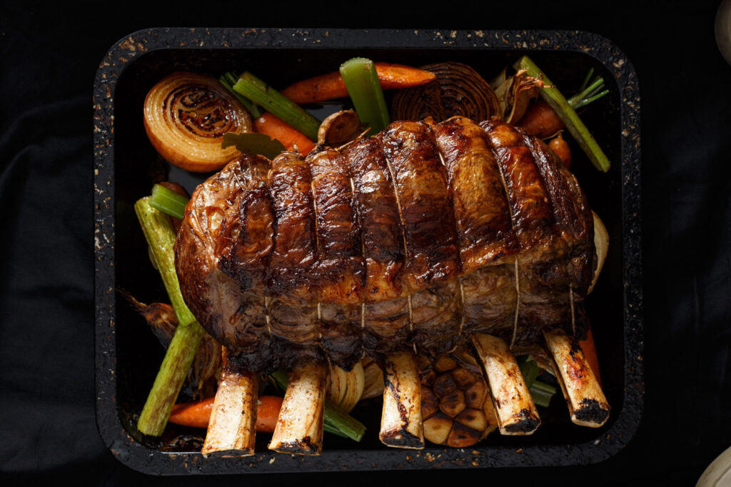 Roasted rack of meat with vegetables in a pan.
