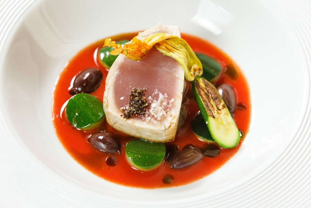 Seared tuna with zucchini, olives, and red sauce.