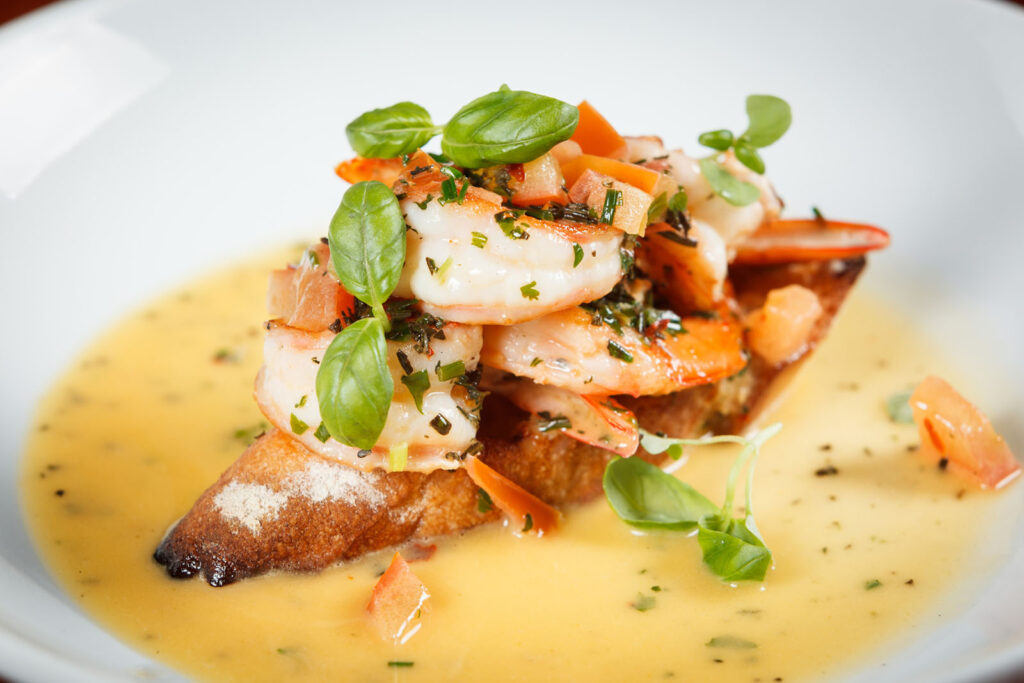 Shrimp on toast with creamy sauce and fresh basil.
