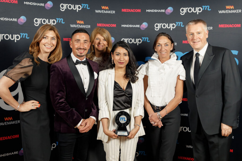 Six people, one holding an award, at a corporate event.