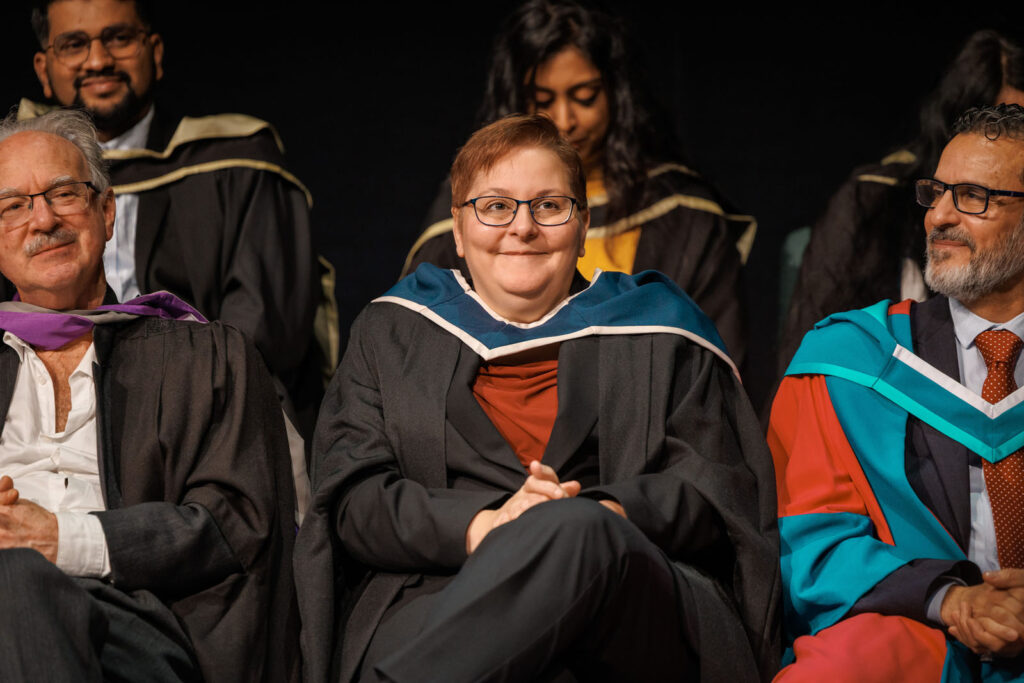 Smiling academics and graduates at a formal ceremony.