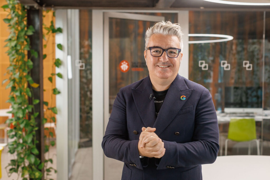 Smiling man in suit with Google pin in office.