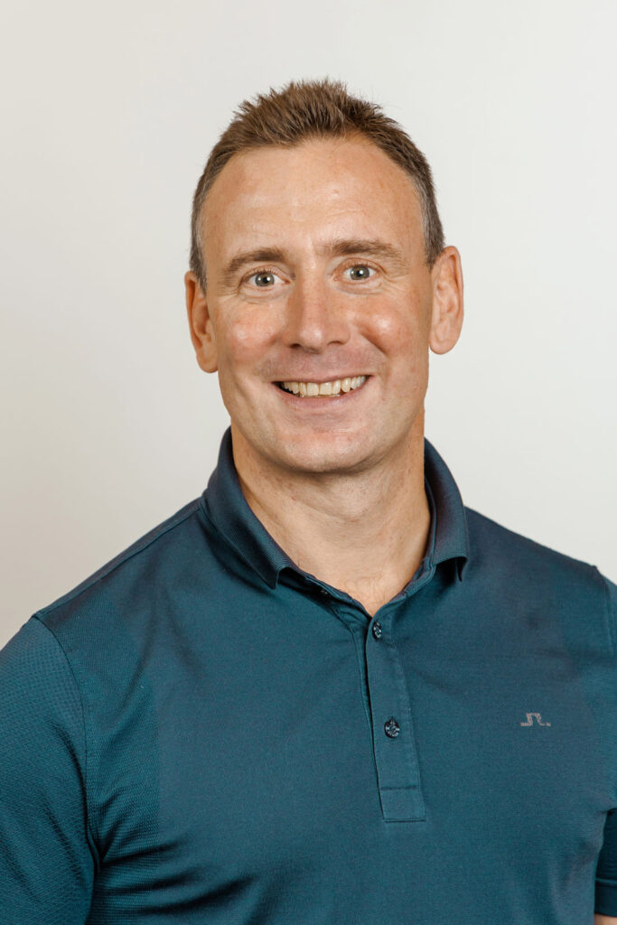 Smiling man in teal polo shirt.
