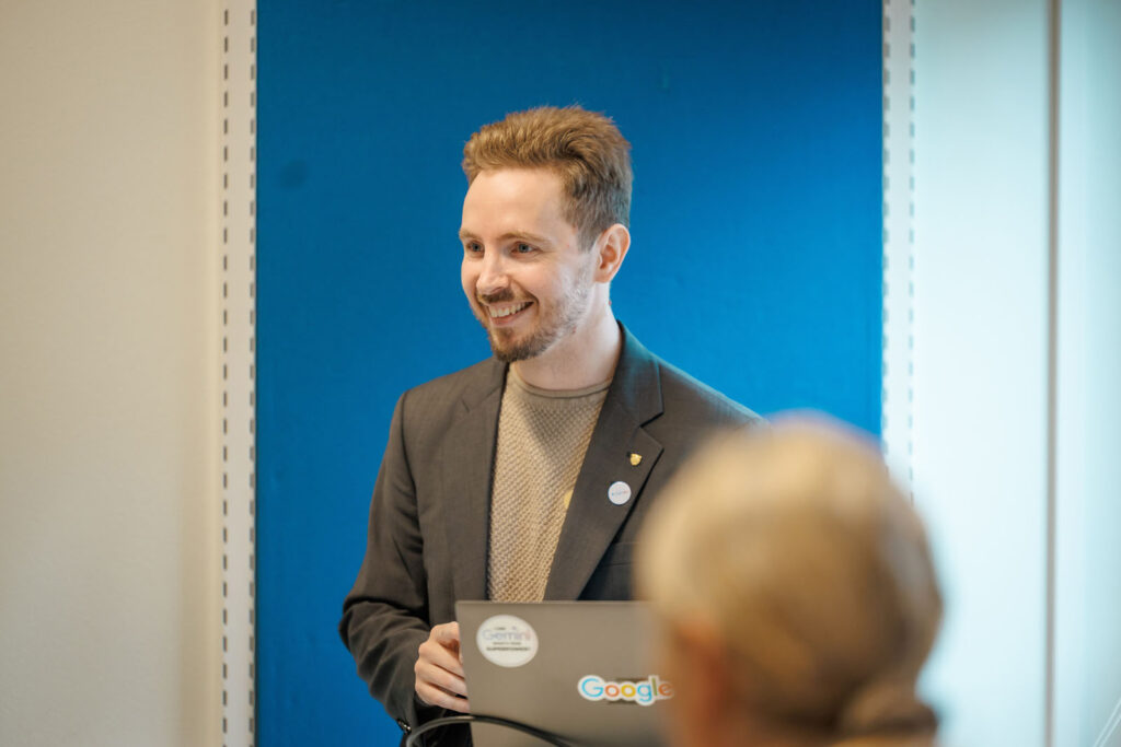 Smiling man presenting with Google laptop.
