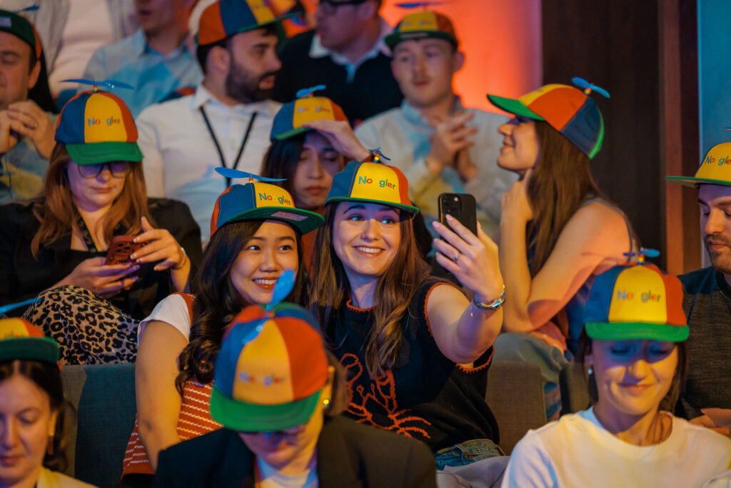 Smiling Nooglers in propeller hats taking a selfie.
