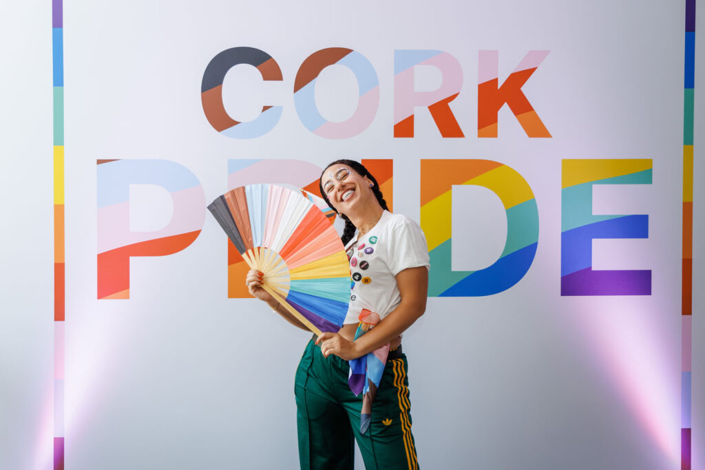 Smiling person holding rainbow fan at Cork Pride.