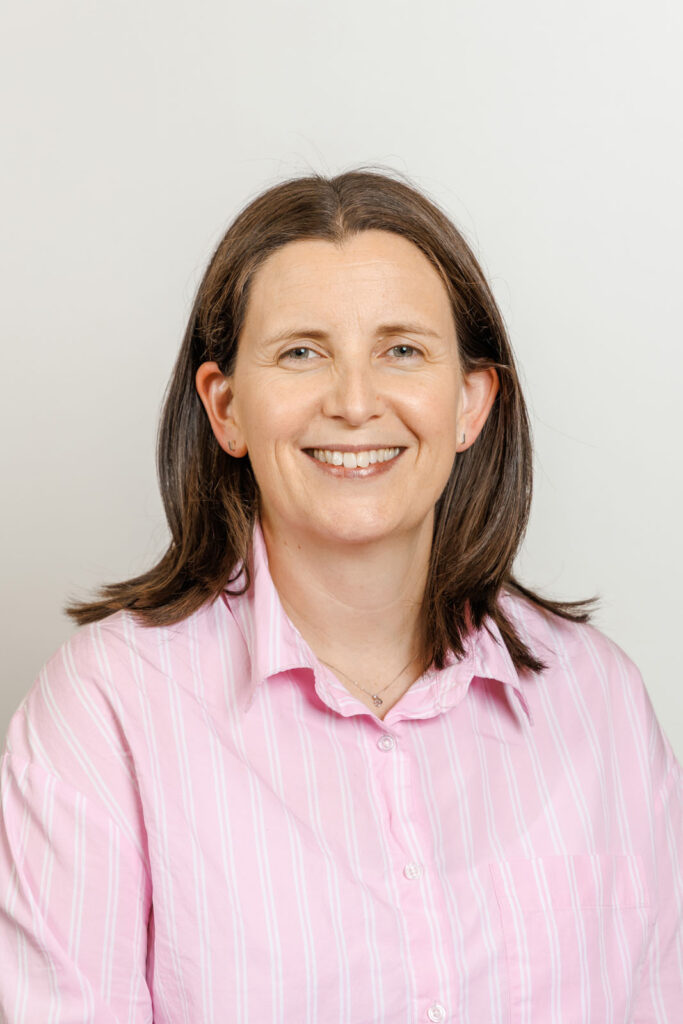 Smiling woman in pink striped shirt.