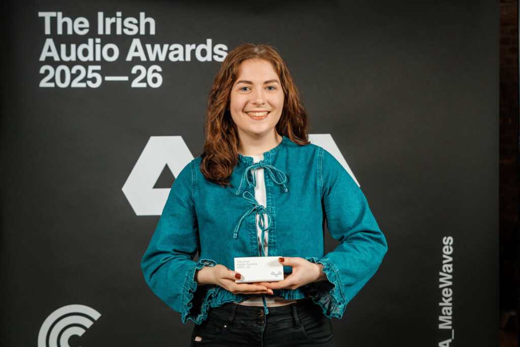 Smiling woman with award box at Irish Audio Awards.