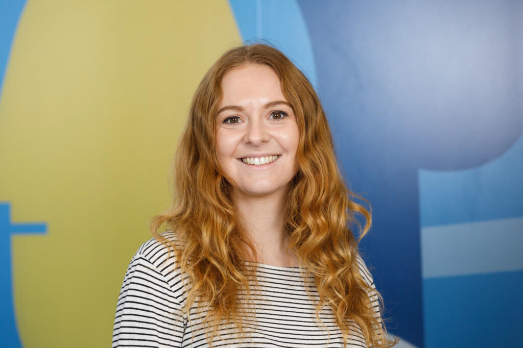 Smiling woman with long hair against a colorful background.