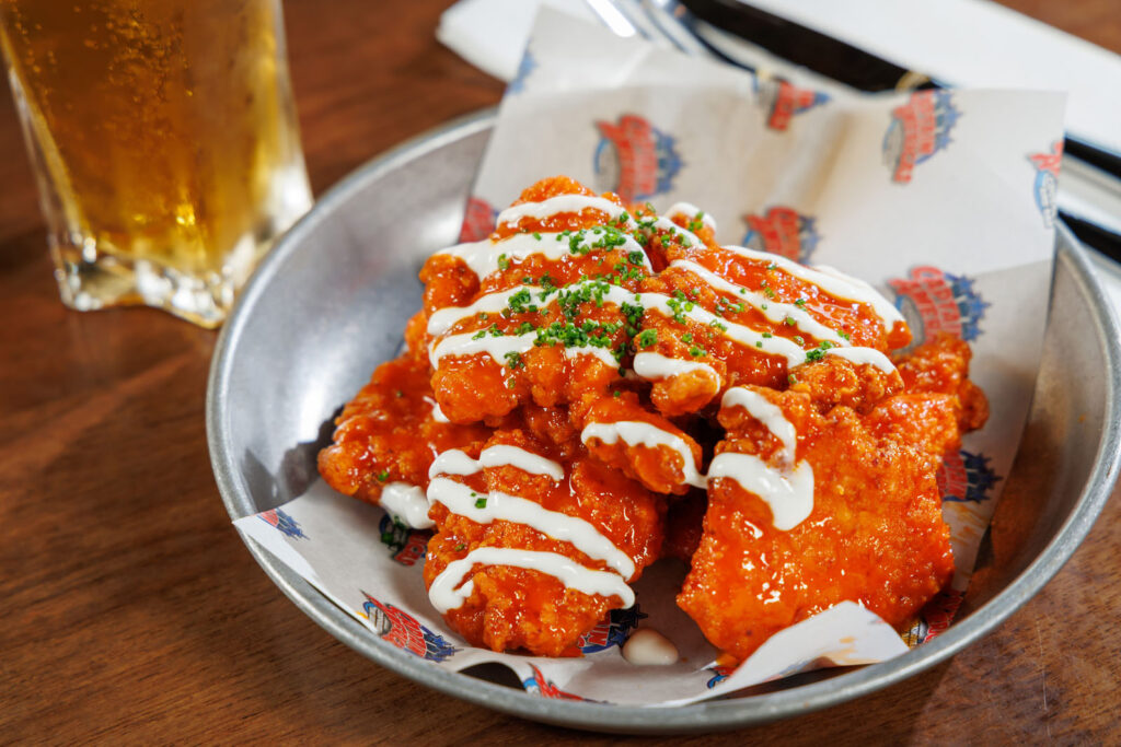 Spicy buffalo wings with sauce and beer.