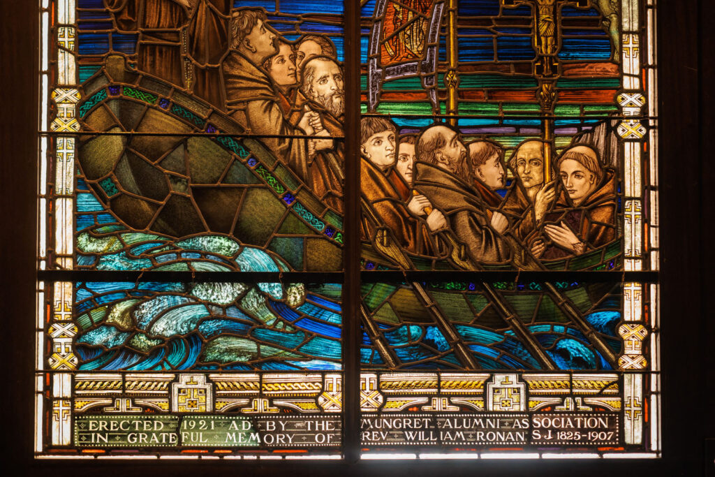 Stained glass window depicting men in a boat on a stormy sea.