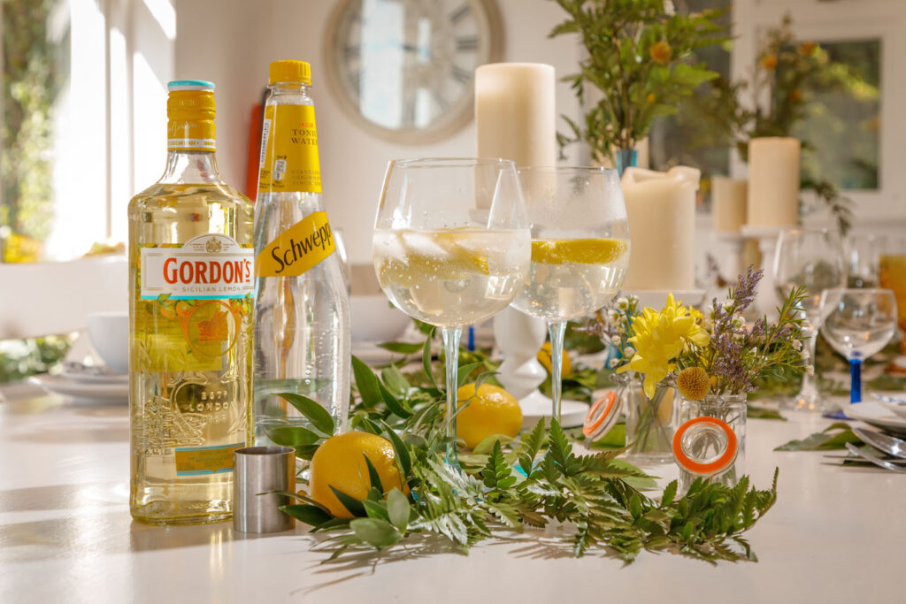 Table set with gin, tonic, lemons, and decorative greenery.