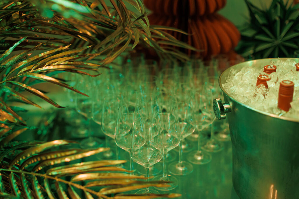 Table with wine glasses, iced drinks, and green-gold decorations.