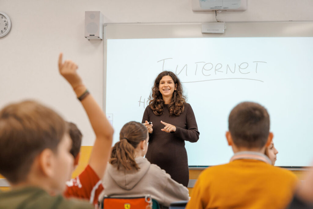 Teacher explains "Internet" to students, one raises hand.