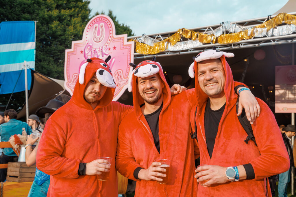 Three men in red animal costumes enjoying a festival.