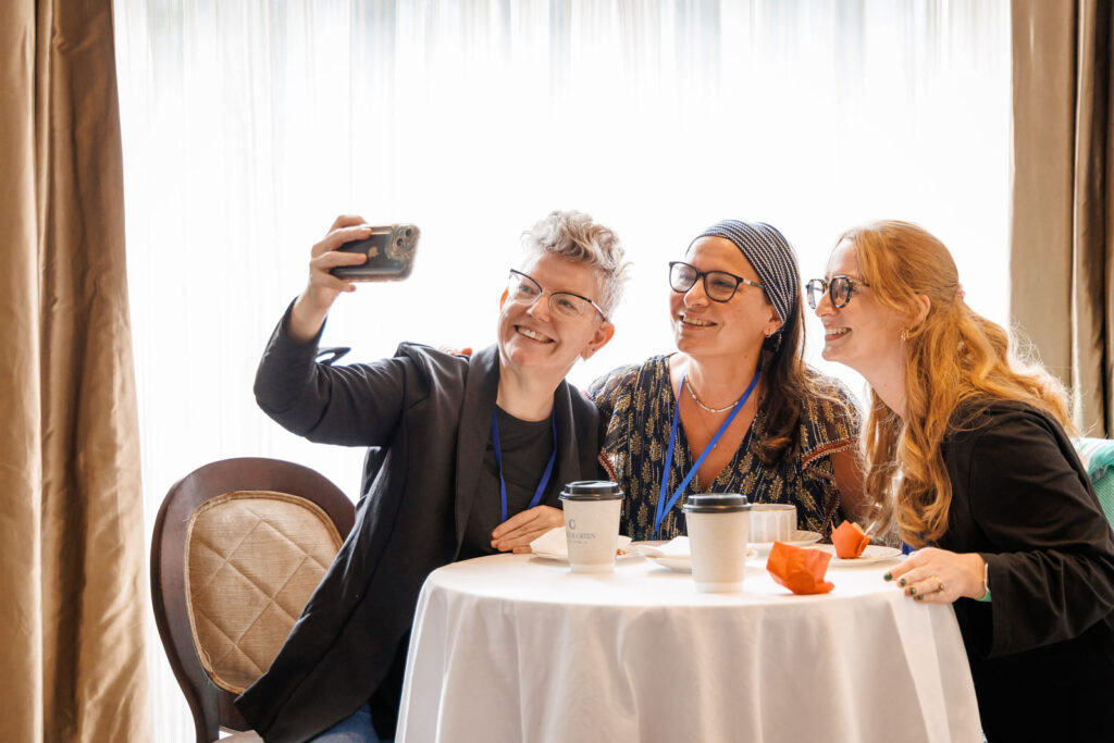 Three women smiling, taking a selfie.