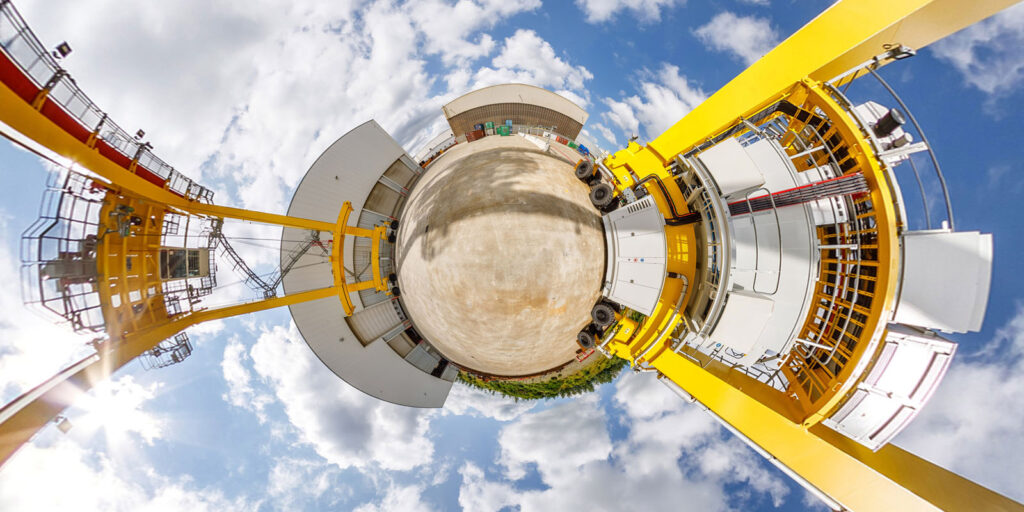 Tiny planet view of industrial site with yellow machinery.