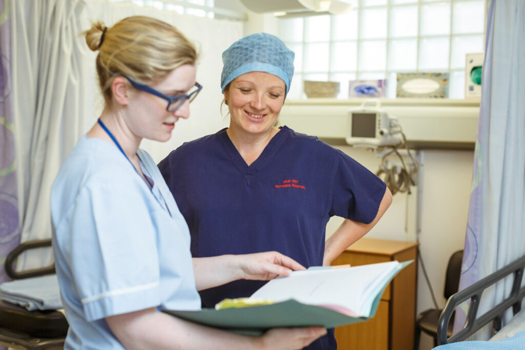 Two medical professionals reviewing patient records in a hospital setting.