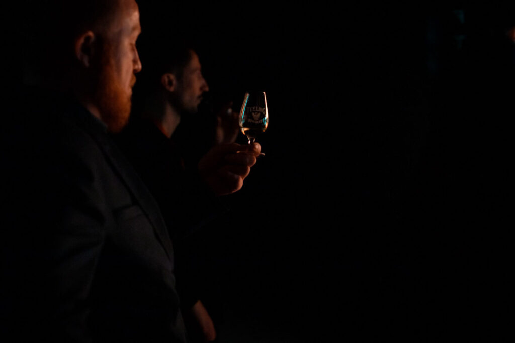 Two men enjoying whiskey in a dark, intimate setting.